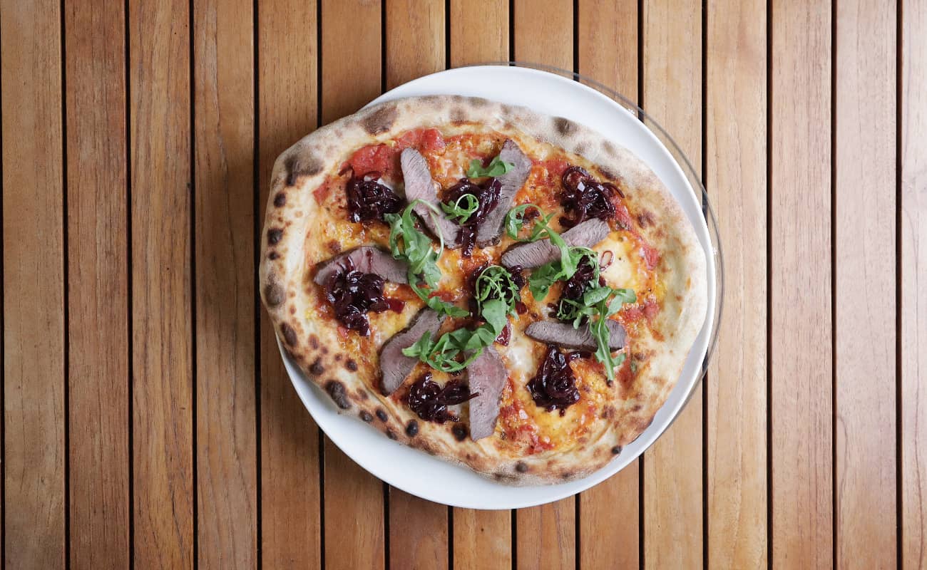 Pizza mit Steak, Zwiebelrelish und Rucola